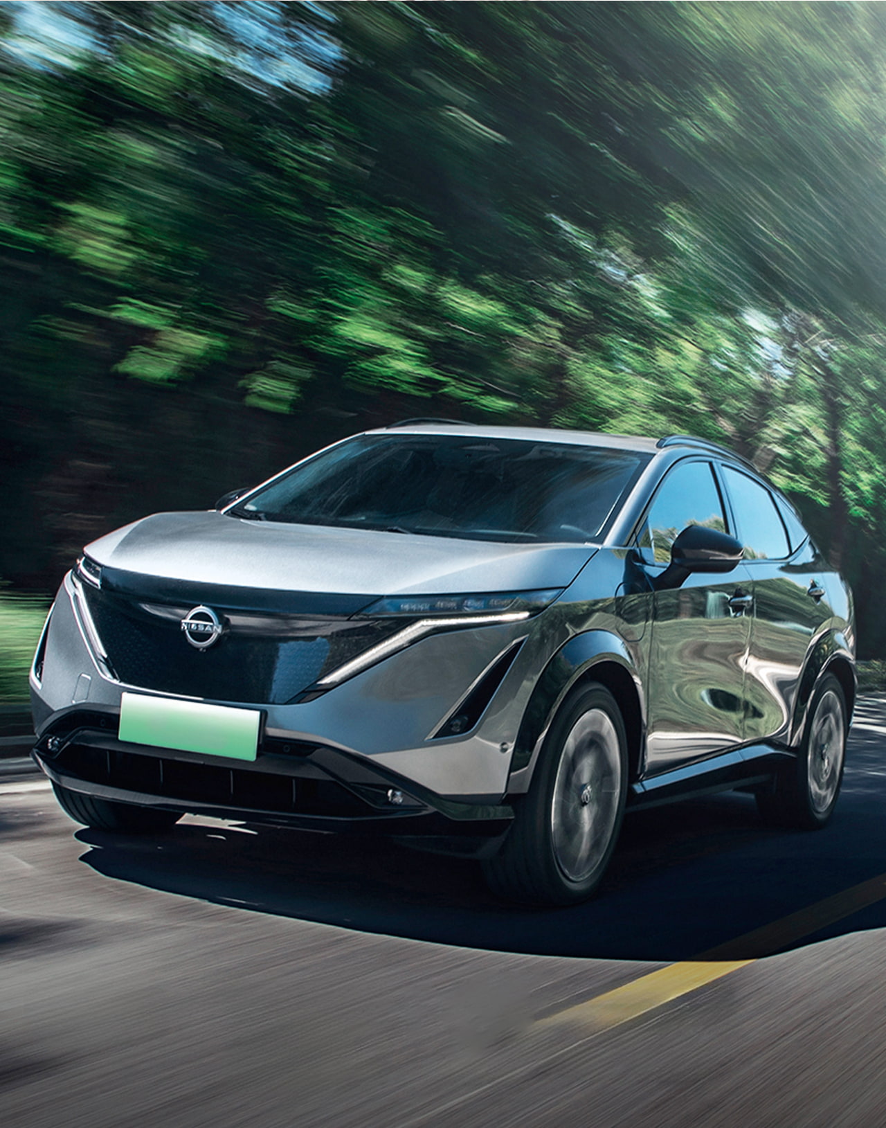 Nissan Ariya в сером цвете едет по дороге